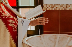 prêtre bénissant l'eau du baptême